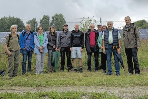 Die Gruppe von Teilnehmern zeigte sich vor dem Zaun zu der soeben besichtigten Solar-Freiflächenanlage