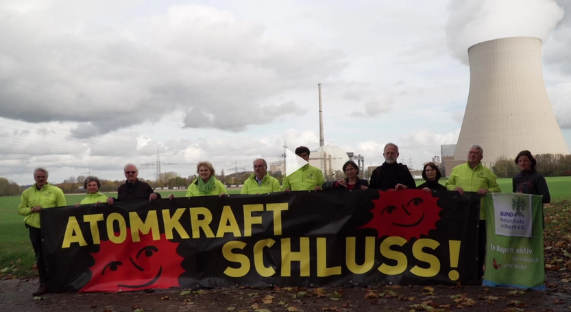 BUND Naturschutz Aktivisten stehen in Sichtweite des Atomkraftwerks Ohu und halten gemeinsam ein Banner mit der Aufschrift "Atomkraft SCHLUSS" hoch