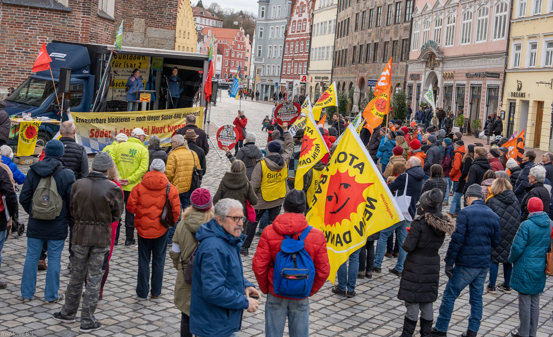 Kundgebungsteilnehmer mit bunten Fahnen und Plakaten in der Landshuter Altstadt vor der fahrbaren Bühne