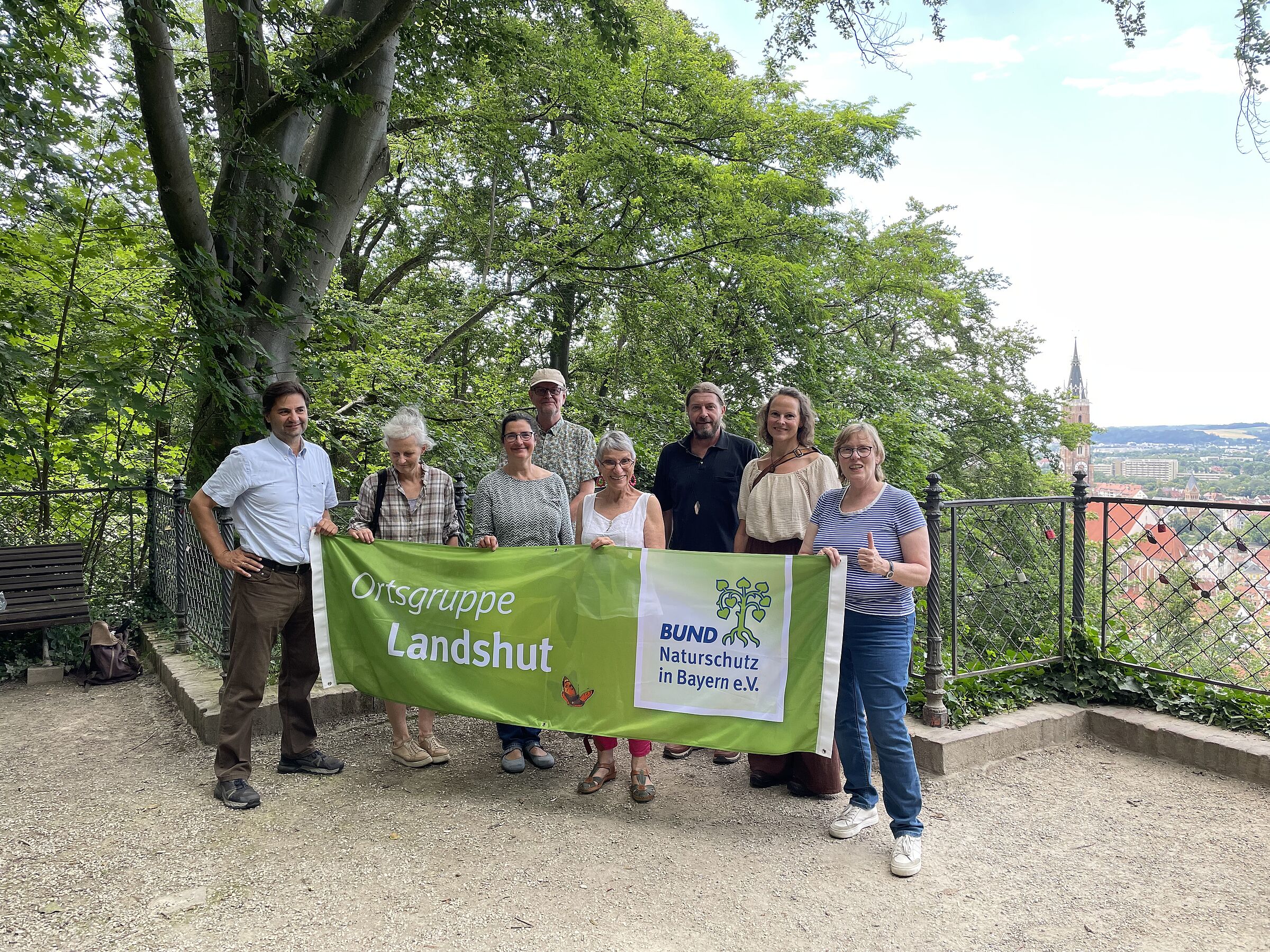 Mitglieder der OG Landshut stehen am Aussichtspunkt des Hofgartens und halten ein Transparent mit der Aufschrift "BUND Naturschutz in Bayern e.V. Ortsgruppe Landshut" hoch